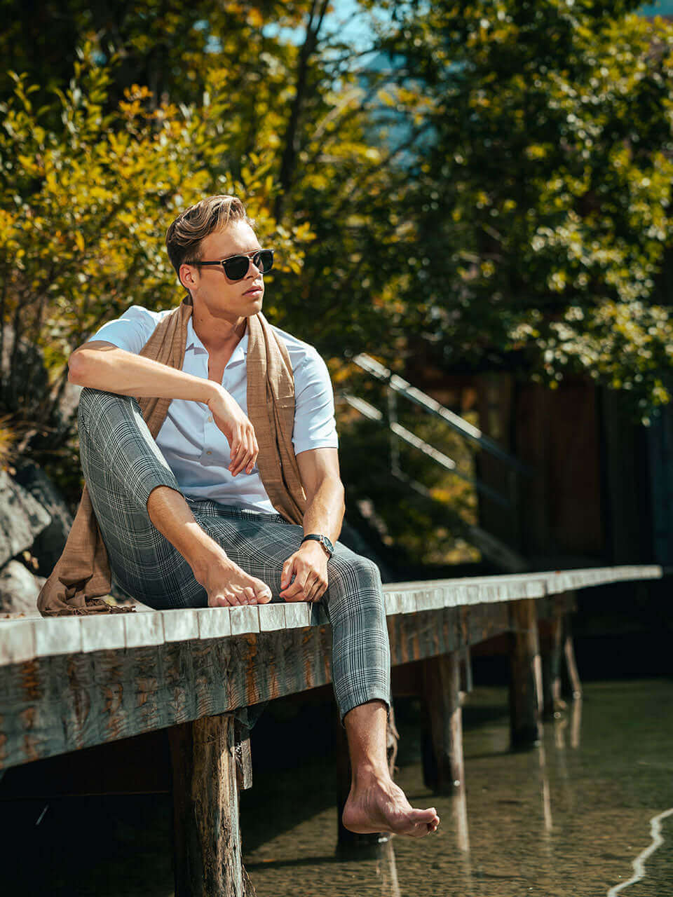 A man wearing a wooden sunglasses relaxes on a dock, enjoying the serene waterfront view.