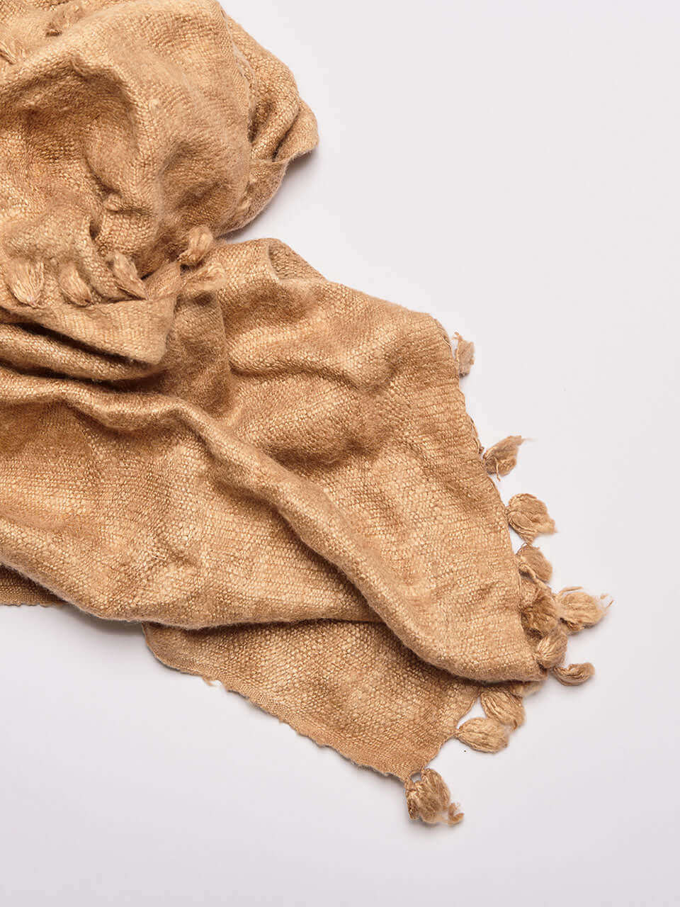 A beige Eri silk shawl spread out on a surface, highlighting its soft texture and natural color.
