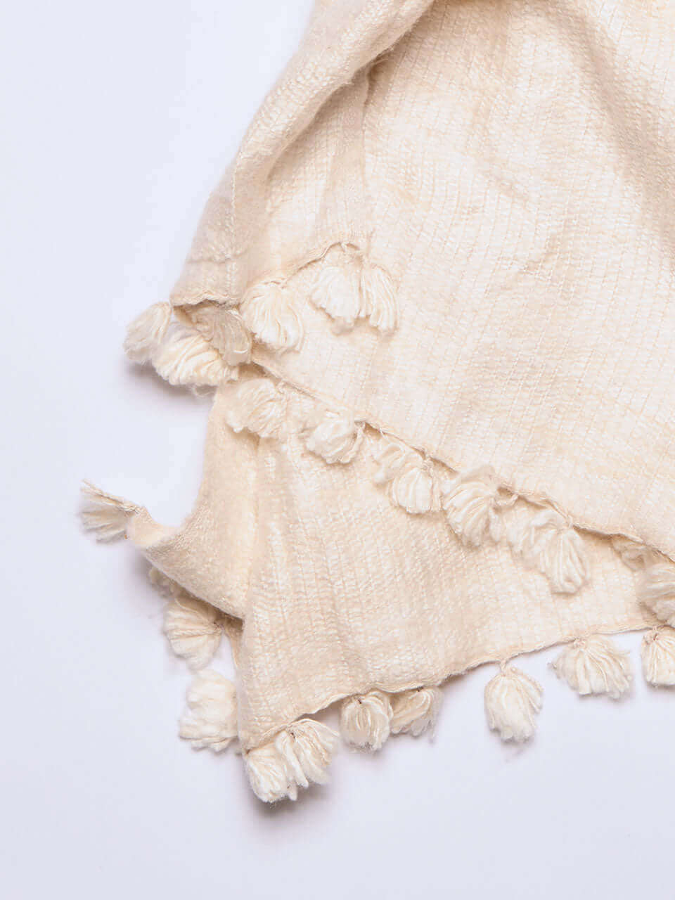 A white Eri silk shawl spread out on a surface, highlighting its soft texture and natural color.