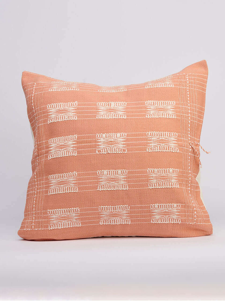 A pink pillow featuring a white geometric print, adding a modern touch to any decor.
