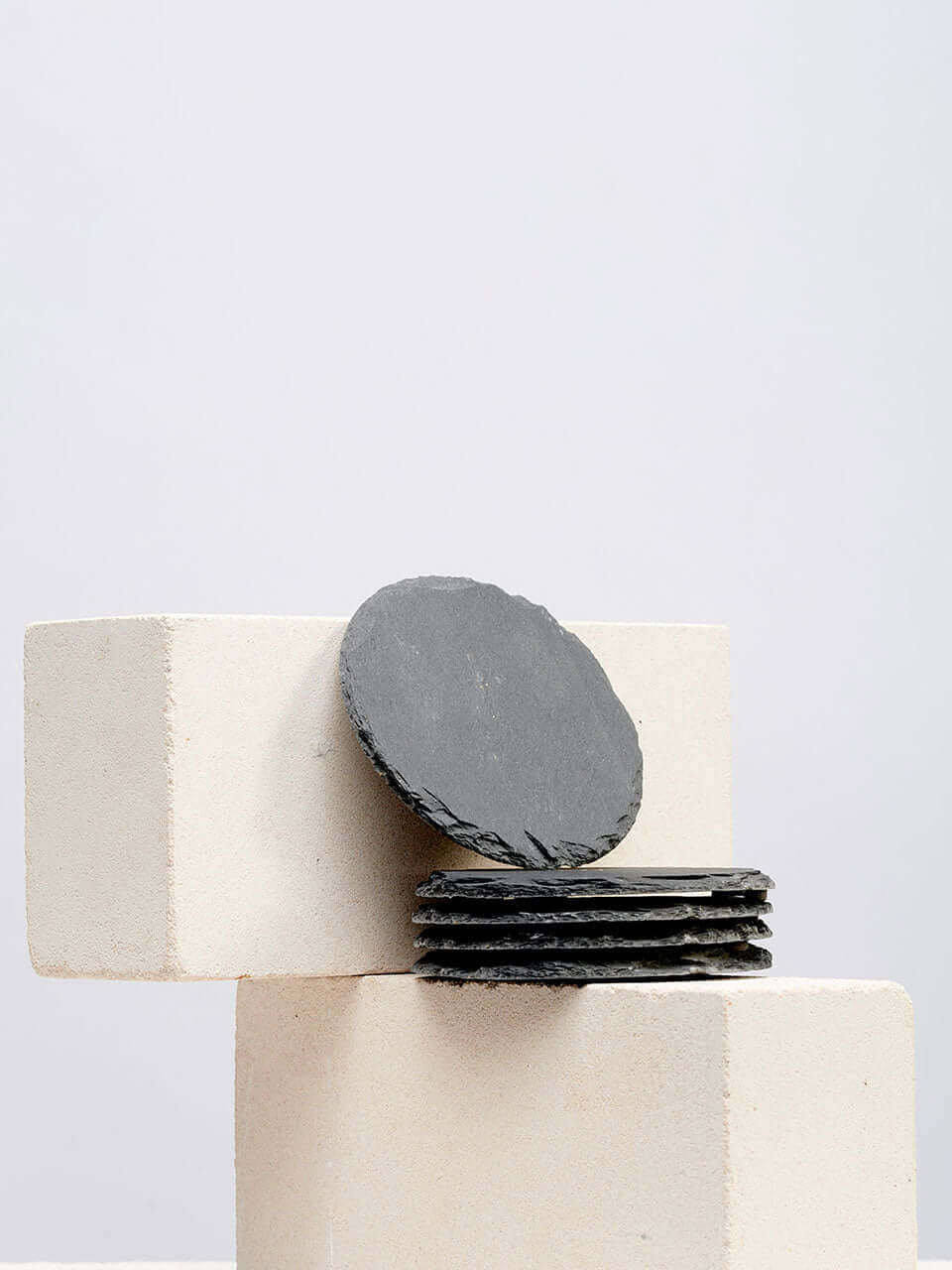 A stack of black slate coasters resting on a white block, showcasing a modern and minimalist design.