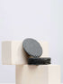 A stack of black slate coasters resting on a white block, showcasing a modern and minimalist design.