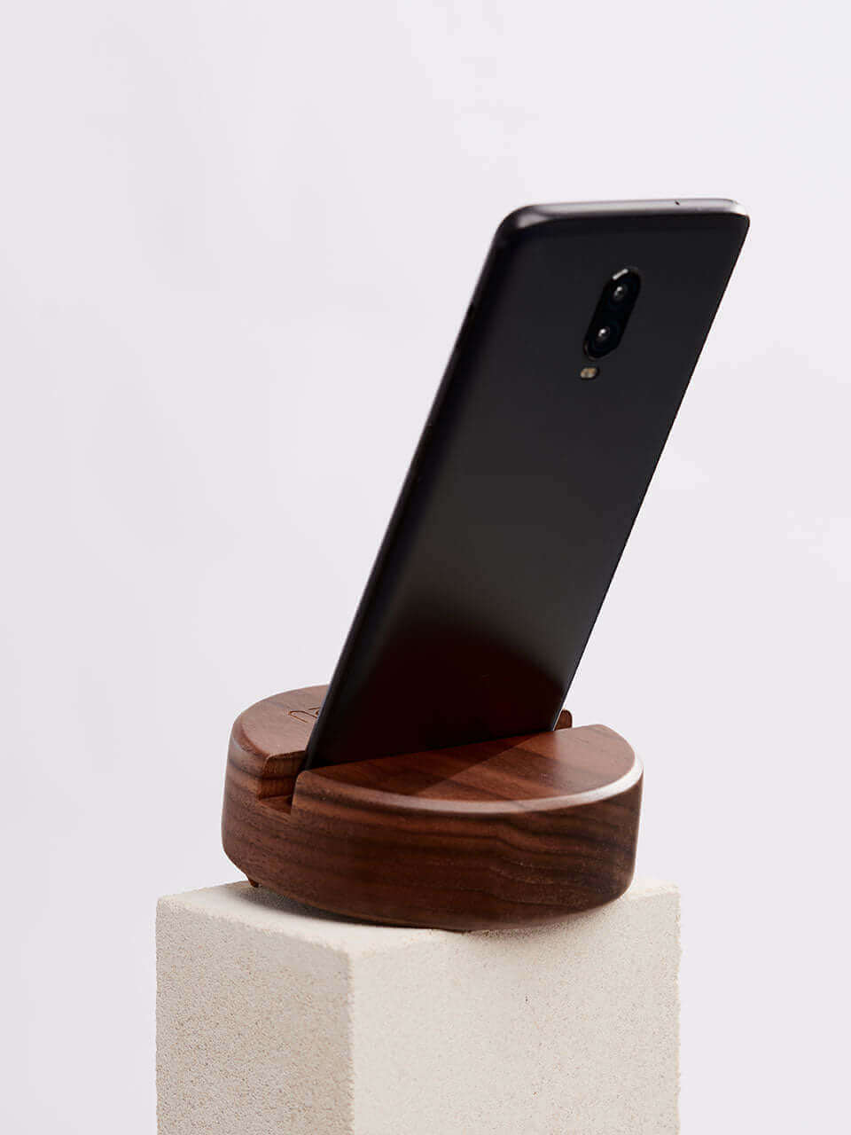 A cell phone placed on a white block, showcasing a blend of technology and natural materials.