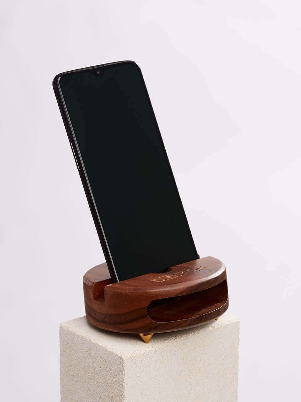 A cell phone placed on a white block, showcasing a blend of technology and natural materials.