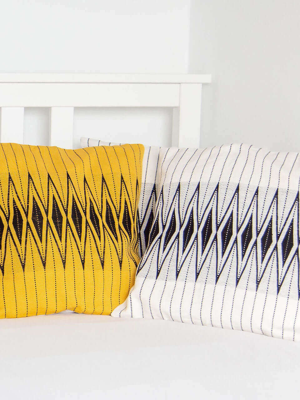 A white bed adorned with yellow and black pillows covers featuring black stripes, creating a vibrant and inviting atmosphere.