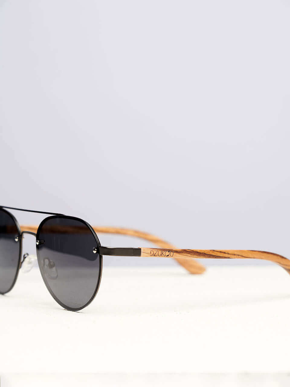 A wooden sunglasses featuring a side view of the stylish wooden frame in a clean surface with a neutral background, showcasing a unique and eco-friendly design.