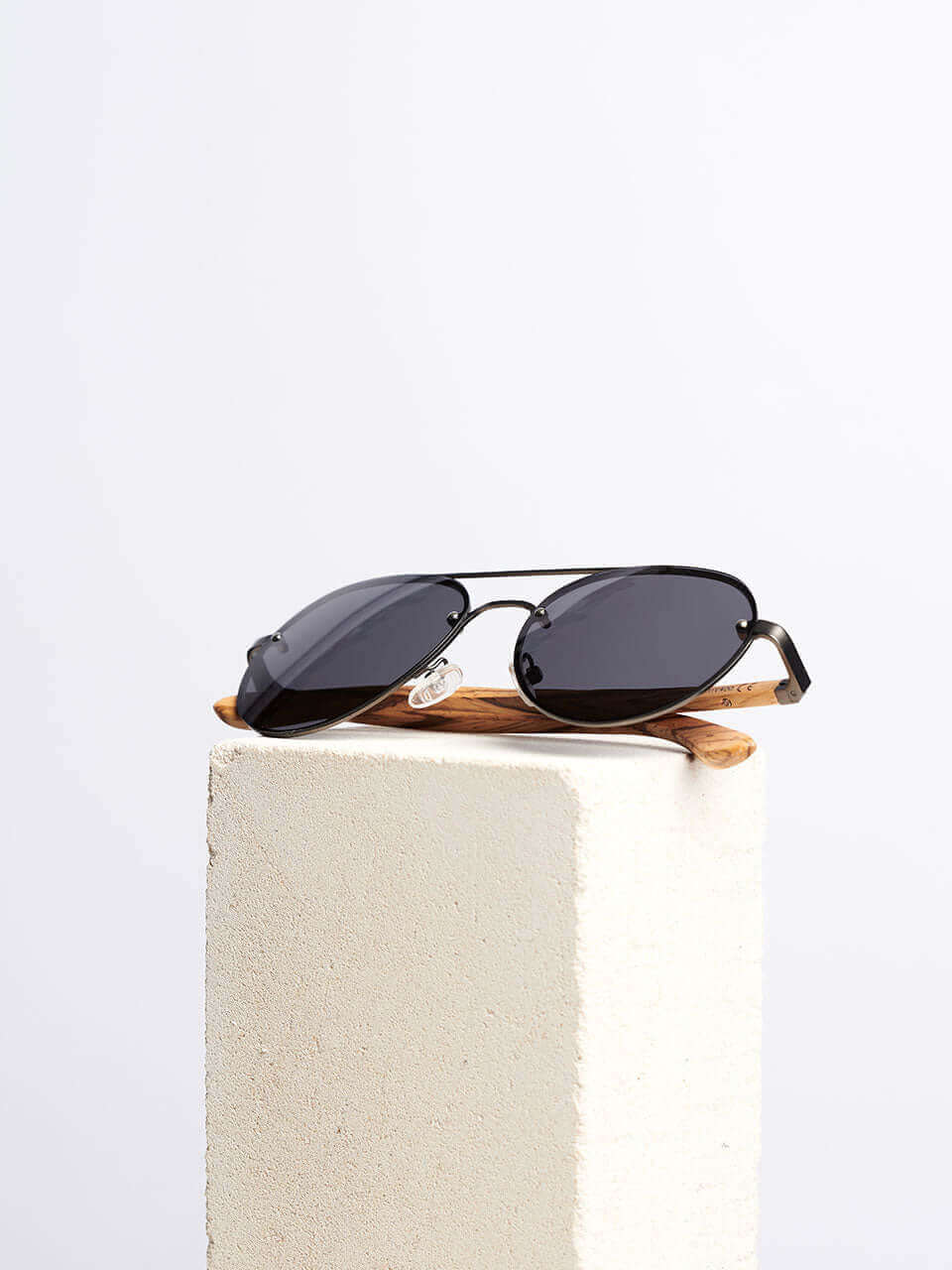 A pair of wooden sunglasses resting on a solid block surface, showcasing their sleek design and reflective lenses.
