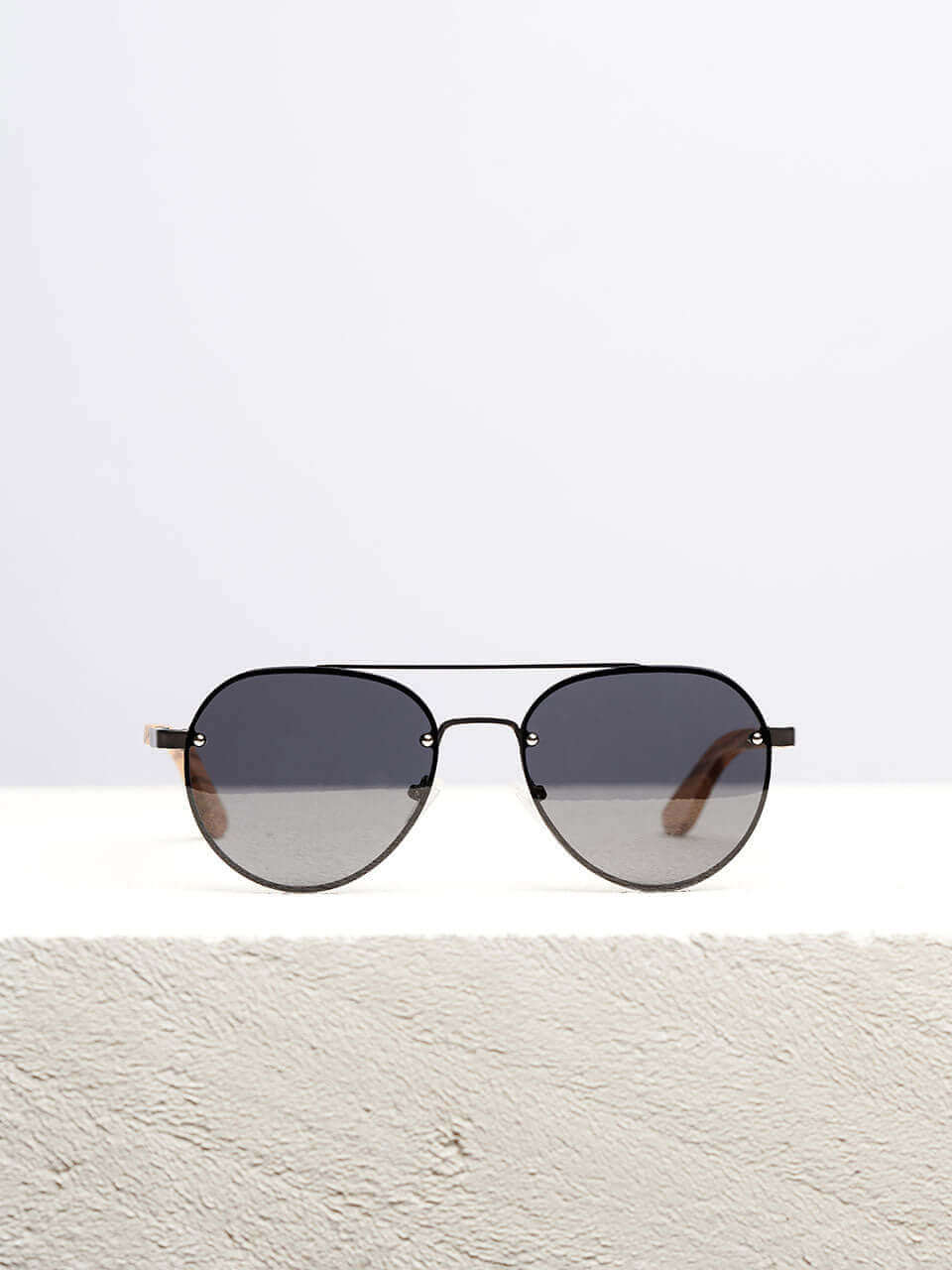 Wooden sunglasses with dark lenses in a neutral background, showcasing a unique and eco-friendly design. Perfect for stylish sun protection.