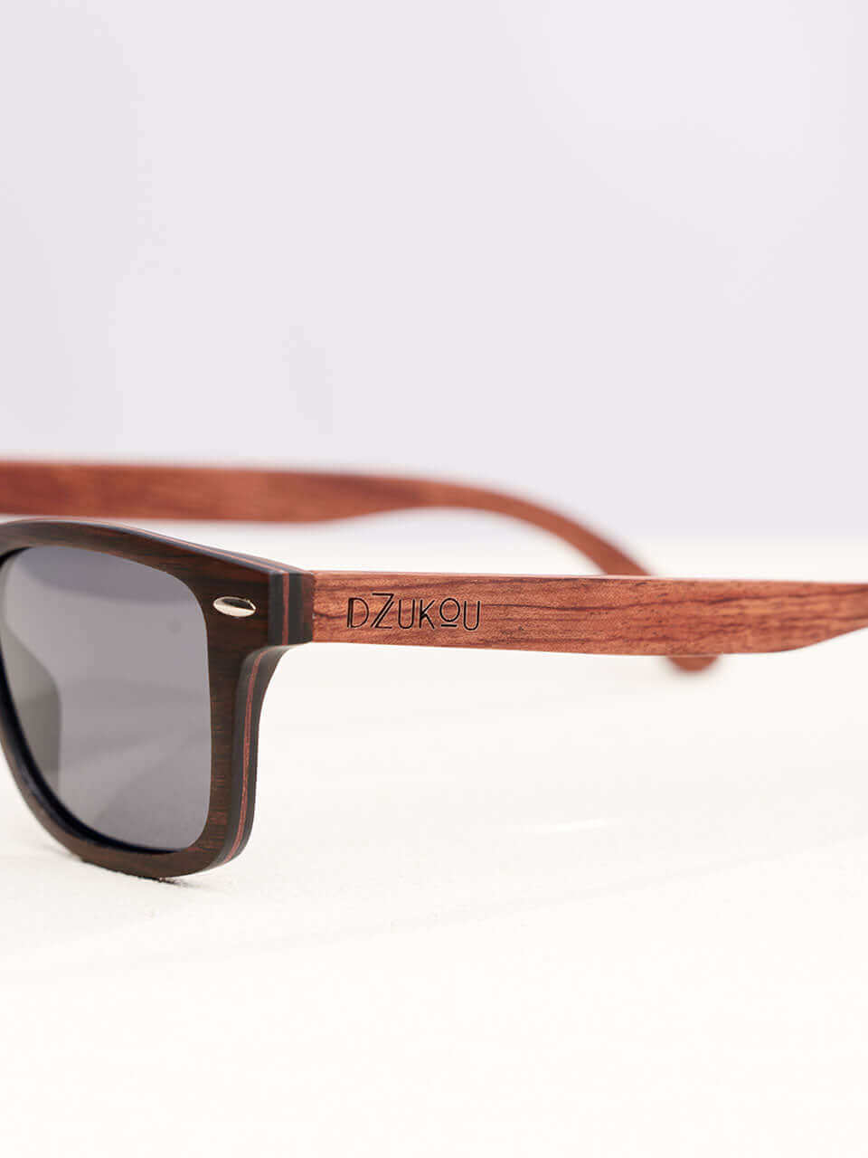 A wooden sunglasses featuring a side view of the stylish wooden frame in a clean surface with a neutral background, showcasing a unique and eco-friendly design.