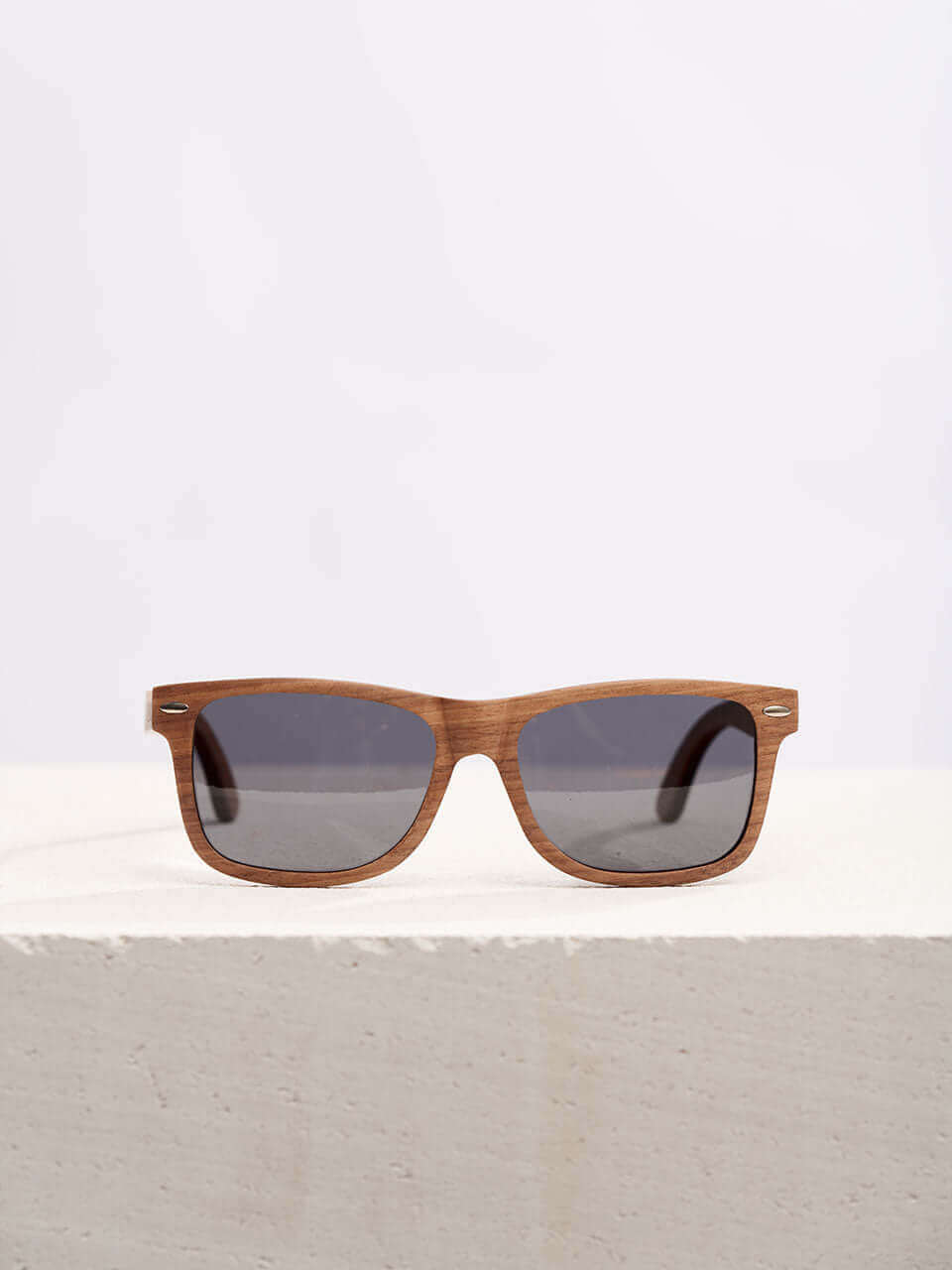 Wooden sunglasses with dark lenses in a neutral background, showcasing a unique and eco-friendly design. Perfect for stylish sun protection.