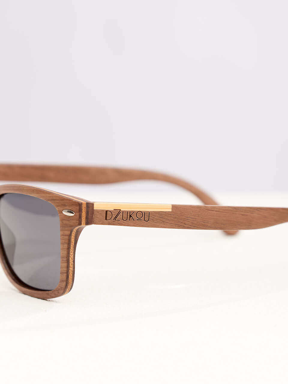 A wooden sunglasses featuring a side view of the stylish wooden frame in a clean surface with a neutral background, showcasing a unique and eco-friendly design.