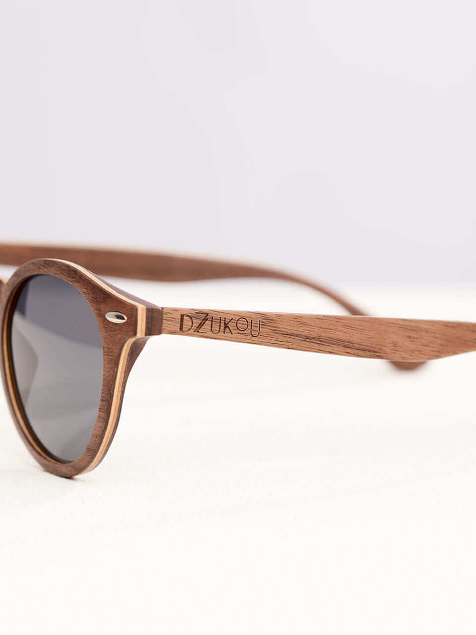 A wooden sunglasses featuring a side view of the stylish wooden frame in a clean surface with a neutral background, showcasing a unique and eco-friendly design.
