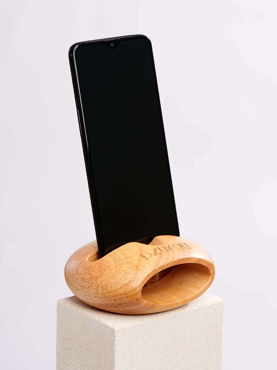 A cell phone placed on a white block, showcasing a blend of technology and natural materials.