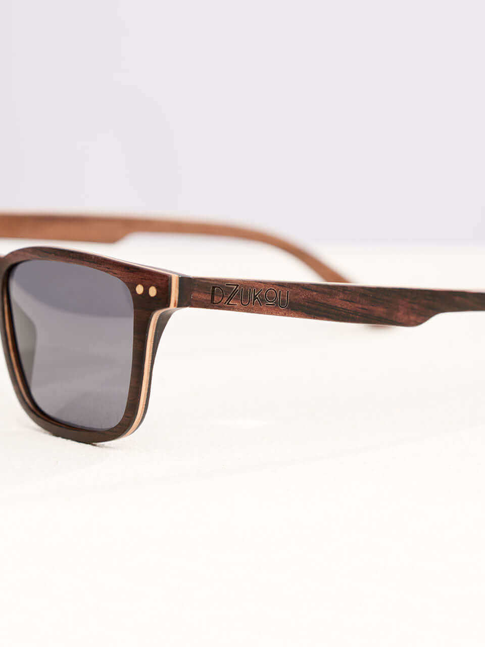A wooden sunglasses featuring a side view of the stylish wooden frame in a clean surface with a neutral background, showcasing a unique and eco-friendly design.