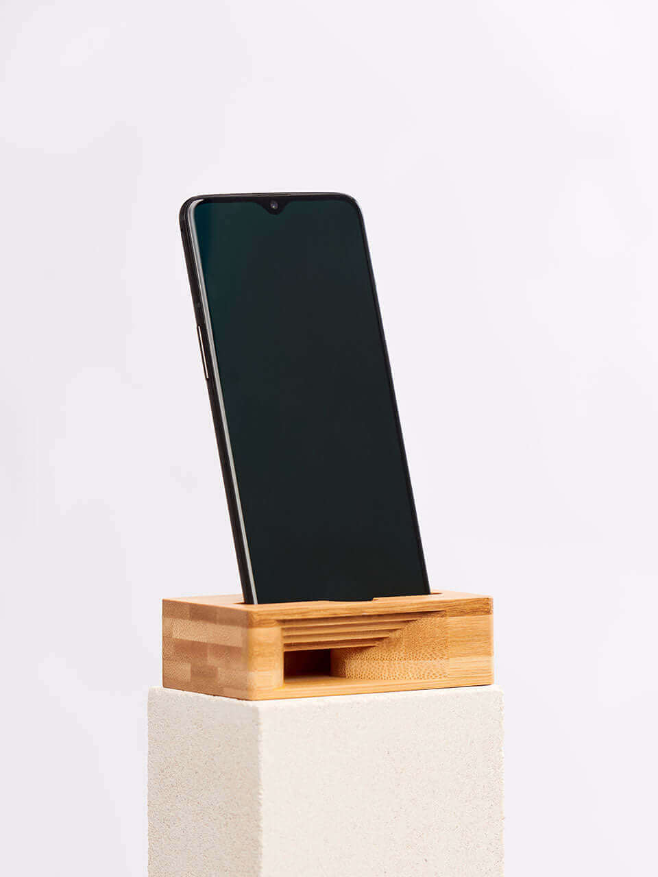 A cell phone placed on a white block, showcasing a blend of technology and natural materials.