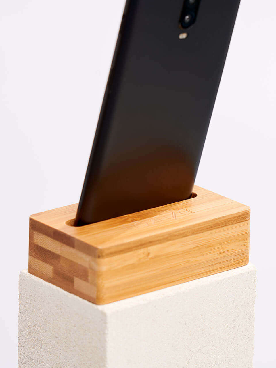 A cell phone placed on a white block, showcasing a blend of technology and natural materials.