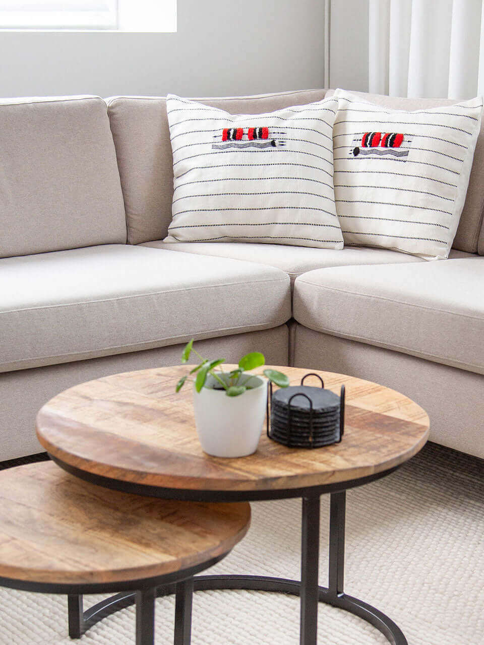 A cozy living room featuring a comfortable couch with white pillow cover with black & red pattern, a stylish coffee table, and a dining table for gatherings.