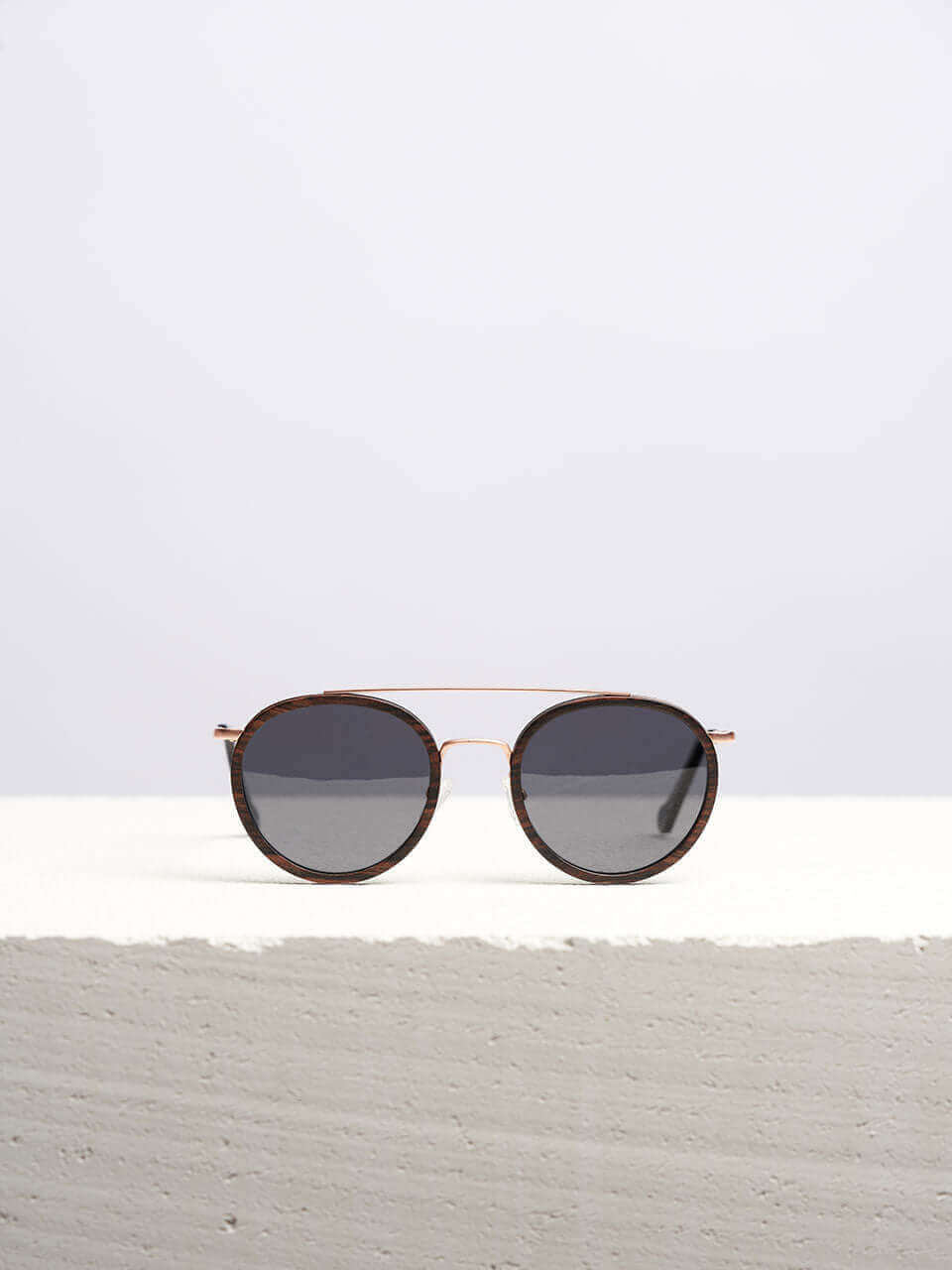 Wooden sunglasses with dark lenses in a neutral background, showcasing a unique and eco-friendly design. Perfect for stylish sun protection.