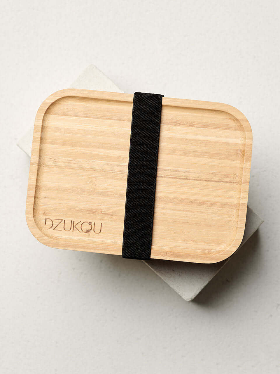 Top view of a bamboo bento box secured with a black strap, showcasing a sustainable and stylish lunch container.