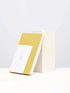A linen notebook place beside a white block with a clean white background.