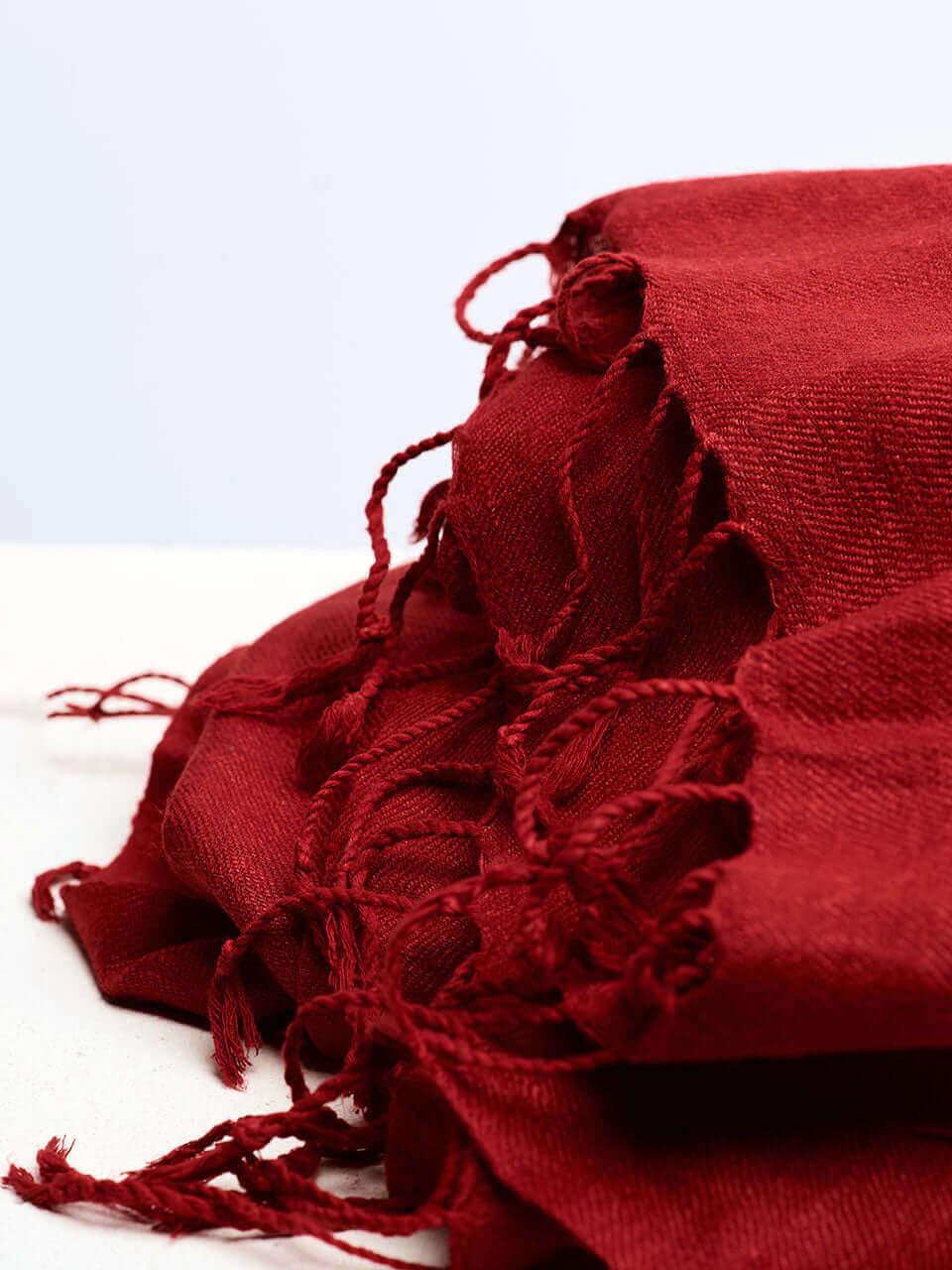 A vibrant pile of red scarves arranged neatly on a clean white surface, showcasing their rich color and texture.