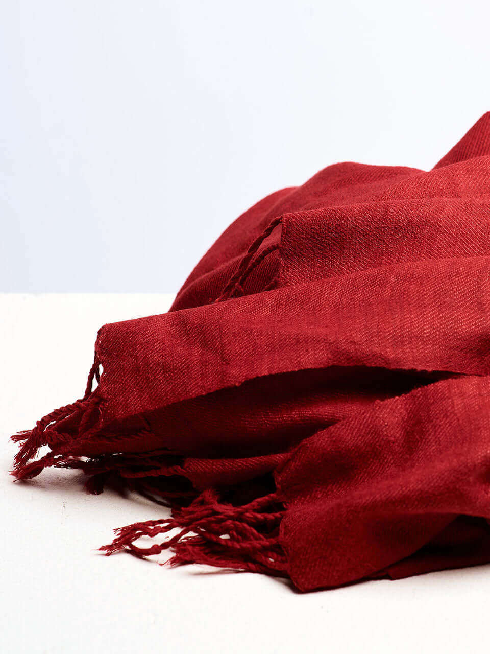 A vibrant pile of red scarves arranged neatly on a clean white surface, showcasing their rich color and texture.
