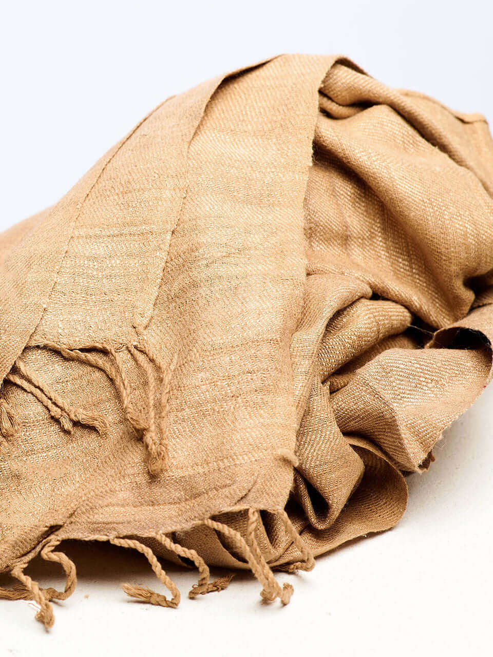 A beige stole resting on a clean white surface, showcasing texture and color contrast.