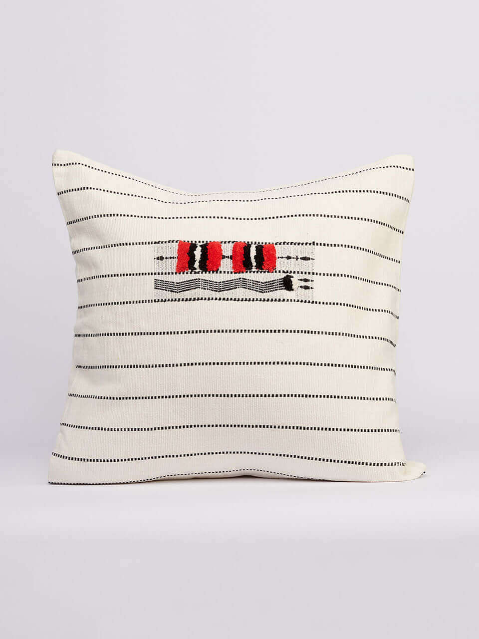 A white pillow cover featuring bold red and black stripes, on a neutral background.