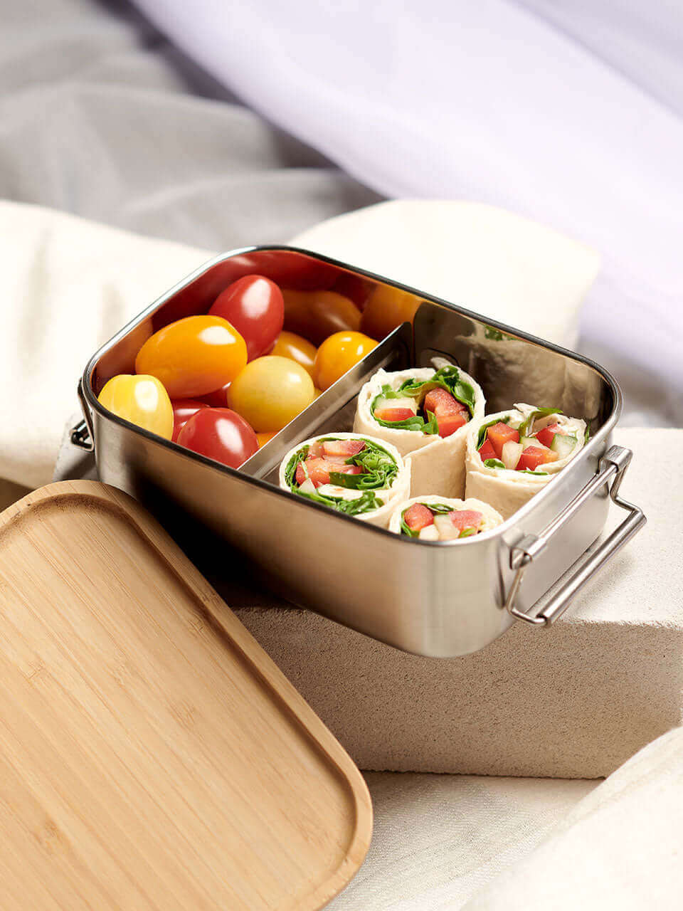 A lunch box containing a sandwich, a fresh salad, and a piece of fruit, arranged neatly for a balanced meal.