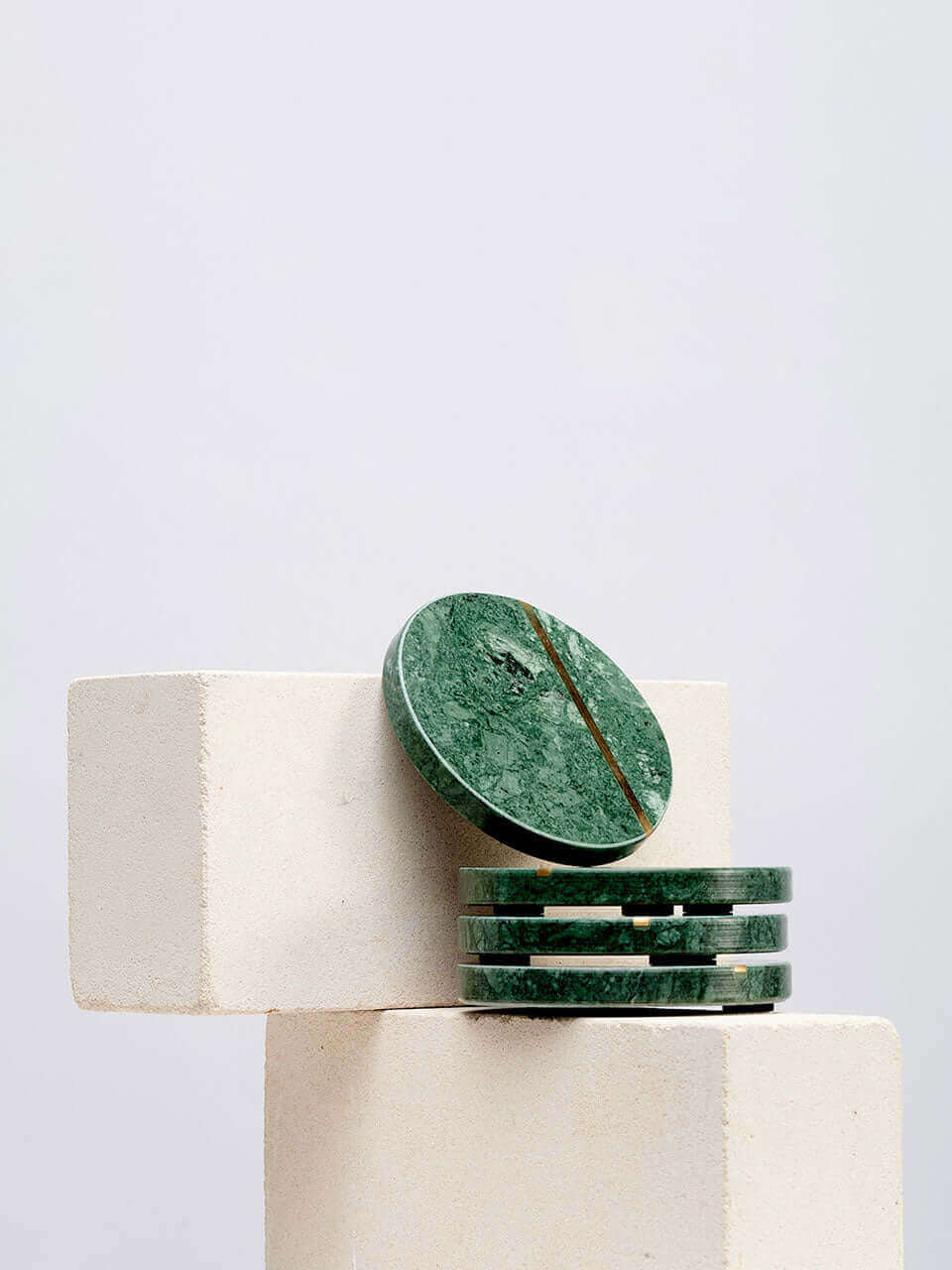 A stack of green marble coasters resting elegantly on a smooth white block.