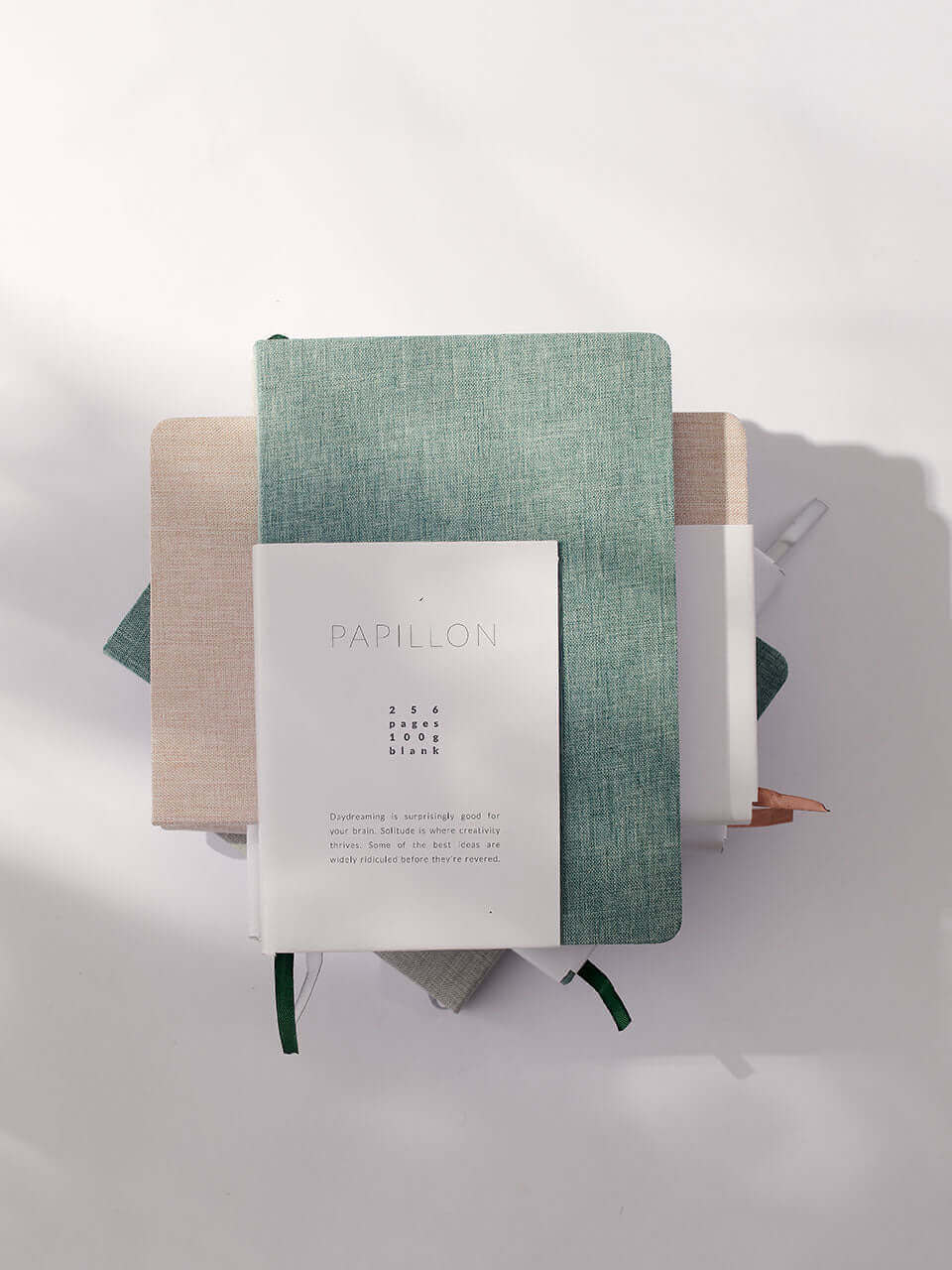 A green-covered linen notebook with blank white pages, resting on a flat surface, ready for writing or drawing.