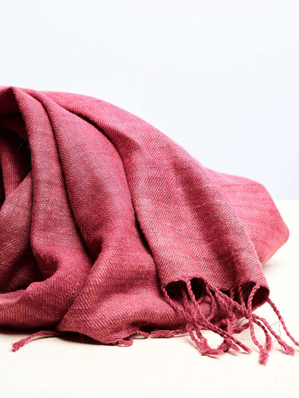 A pink scarf resting on a clean white surface, showcasing texture and color contrast.
