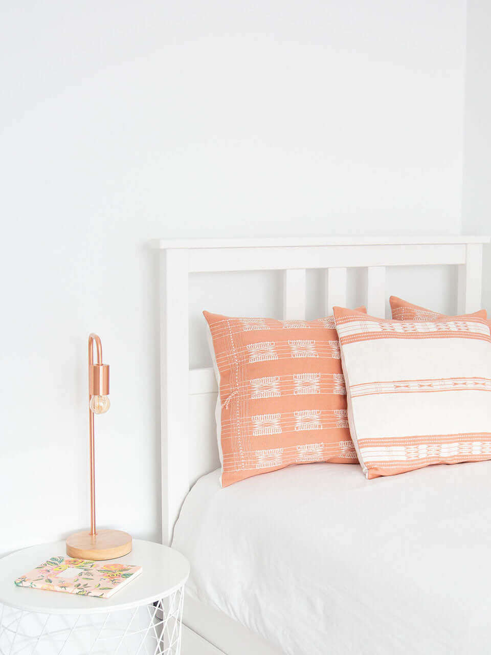 A white bed adorned with pink and white pillows, creating a soft and inviting atmosphere.