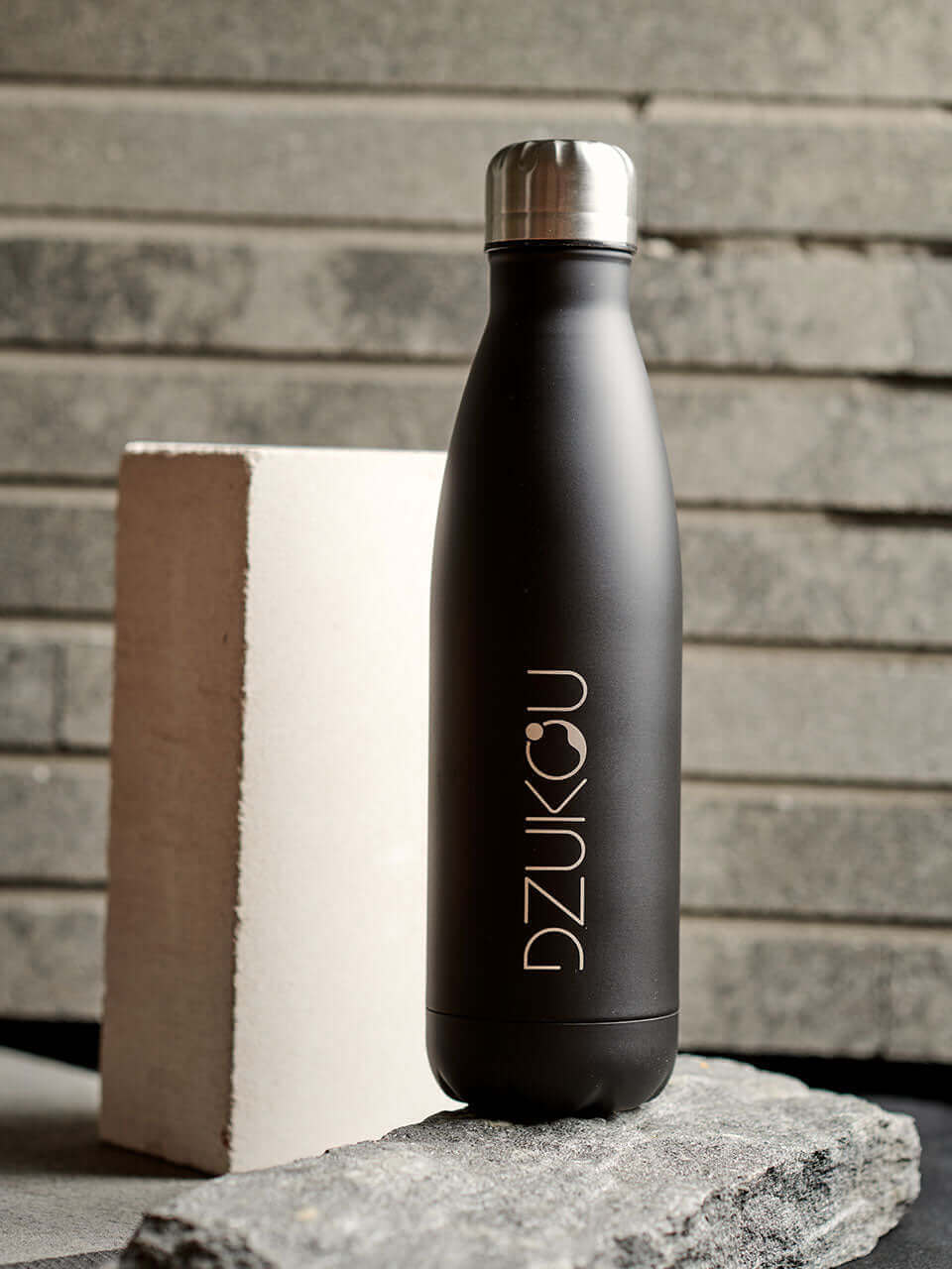 A stainless steel water bottle displayed against a grey background, highlighting its eco-friendly design.