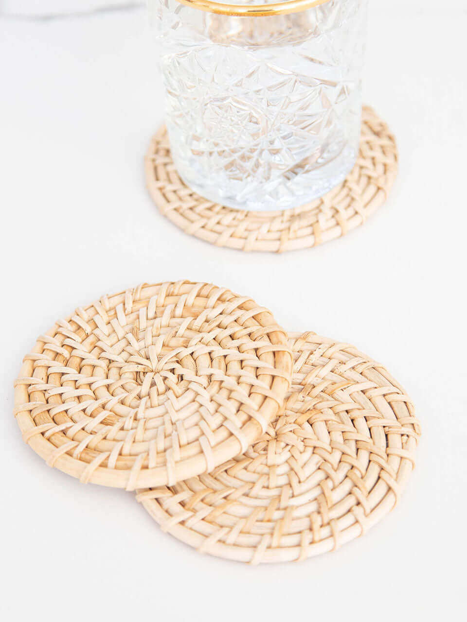 Two cane coasters placed on a glass surface, showcasing a natural and elegant design.