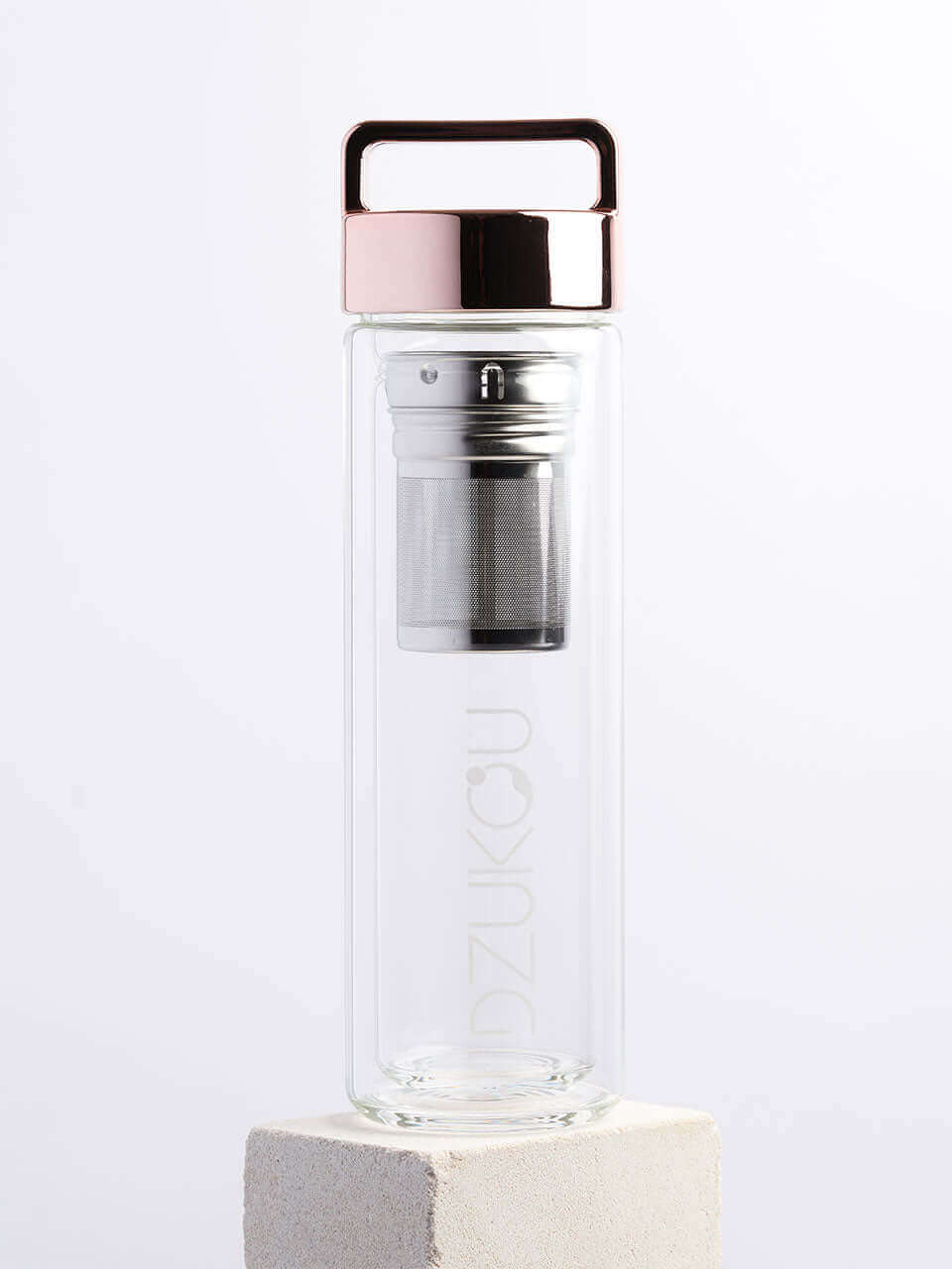A glass bottle featuring both a rose lid and a metal lid in a white background, showcasing a blend of natural and modern materials.