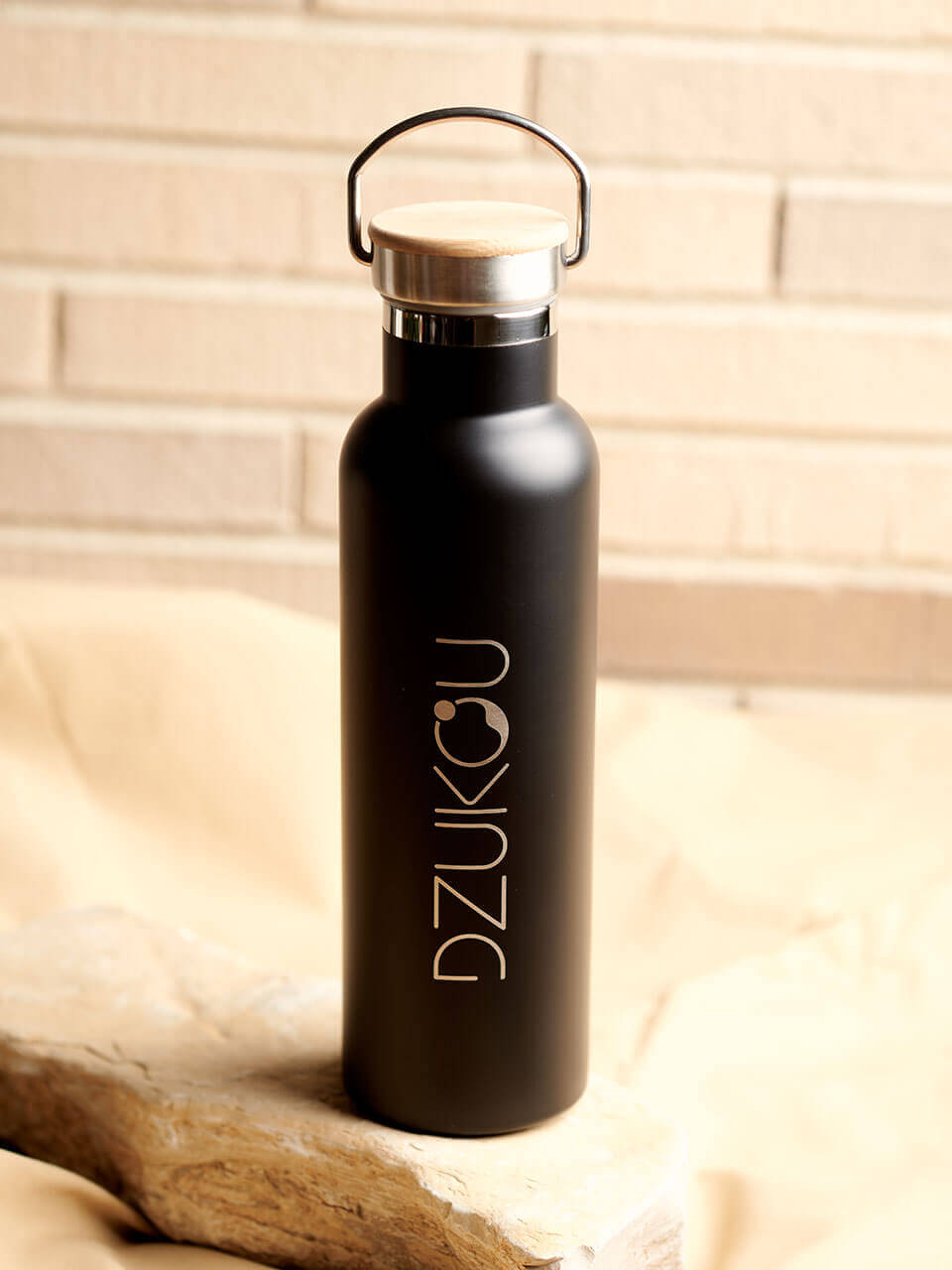 A stainless steel water bottle displayed against a beige background, highlighting its eco-friendly design.