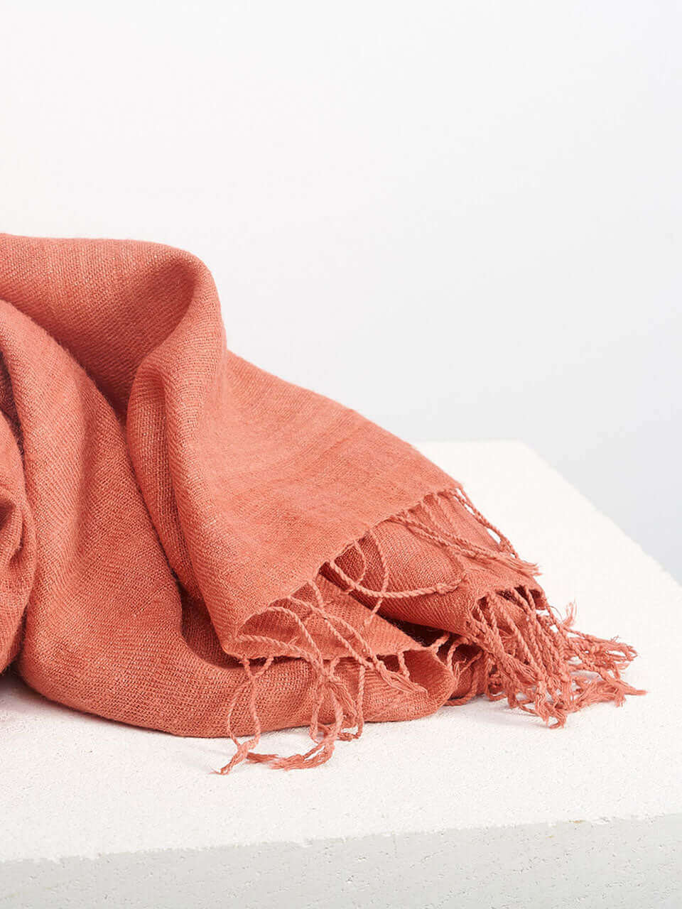 A peach scarf resting on a clean white surface, showcasing texture and color contrast.