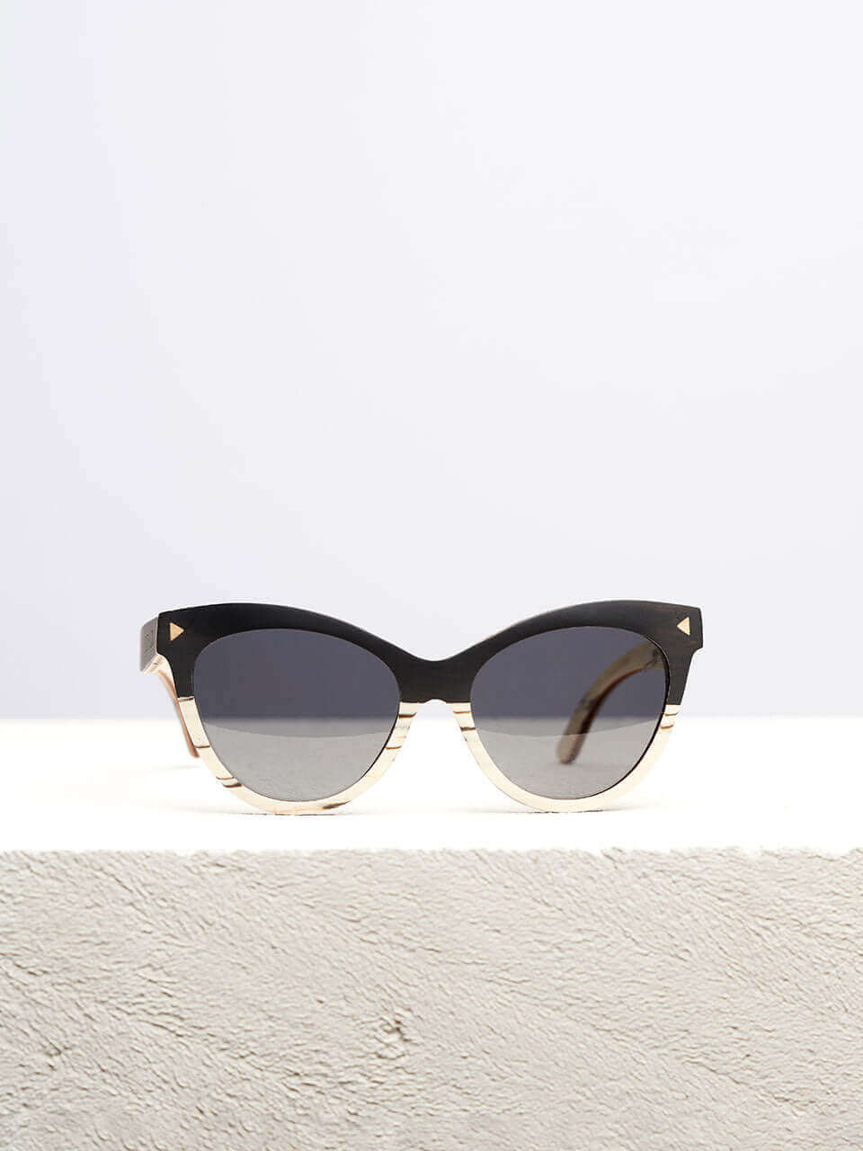 Wooden cat eye sunglass with dark lenses in a neutral background, showcasing a unique and eco-friendly design. Perfect for stylish sun protection.