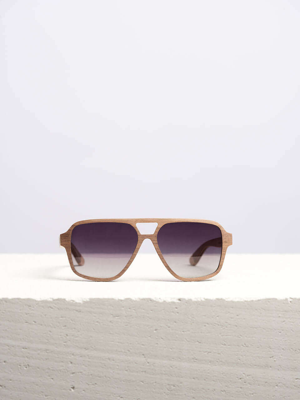 Wooden sunglasses with dark lenses in a neutral background, showcasing a unique and eco-friendly design. Perfect for stylish sun protection.