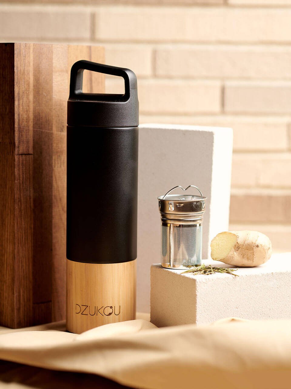 A stainless steel water bottle displayed against a beige background with the infuser on the side, highlighting its eco-friendly design.