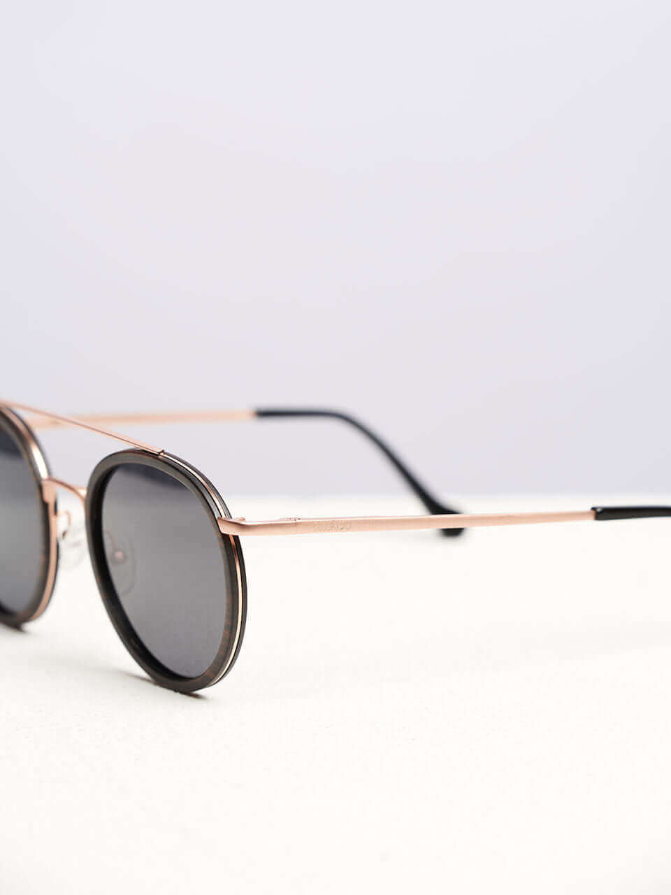 A wooden sunglasses featuring a side view of the stylish wooden frame in a clean surface with a neutral background, showcasing a unique and eco-friendly design.