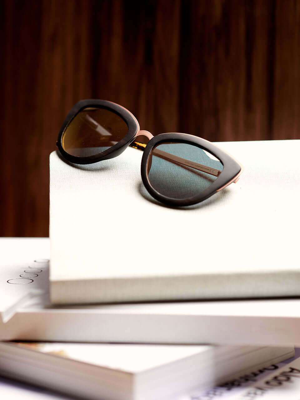 A pair of sunglasses placed on an open book, showcasing a relaxed reading atmosphere.