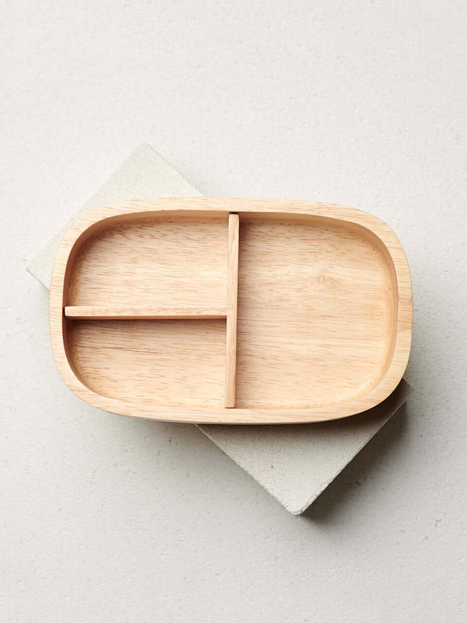 A wooden lunch box featuring three distinct compartments on its surface, designed for organized storage or presentation.