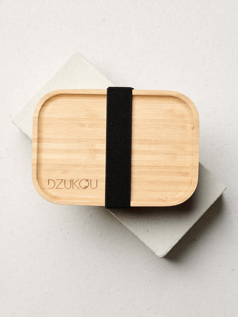 Top view of a bamboo bento box secured with a black strap, showcasing a sustainable and stylish lunch container.