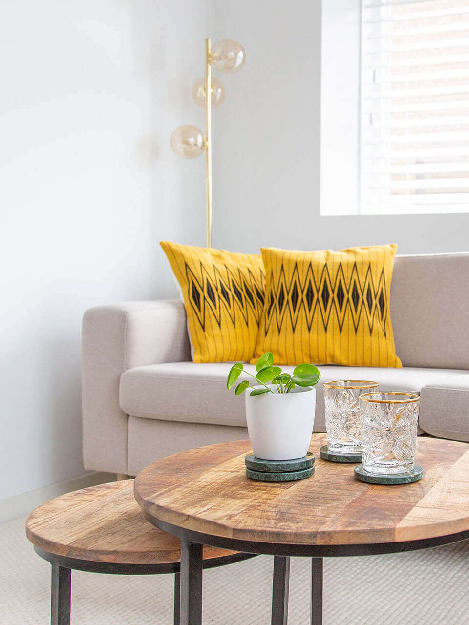 A cozy living room featuring a comfortable couch with yellow pillow cover with black pattern, a stylish coffee table, and a dining table for gatherings.