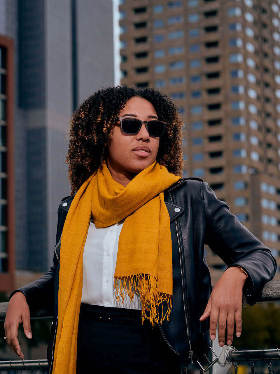 A woman with sunglasses and a yellow scarf, exuding a stylish and confident demeanor.