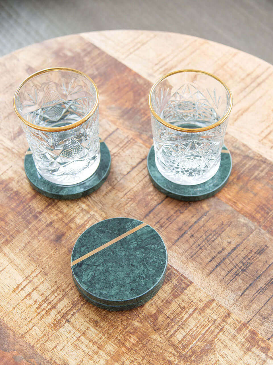 Green marble coasters featuring elegant gold trim on top of a wooden table, adding a touch of sophistication to any table setting.