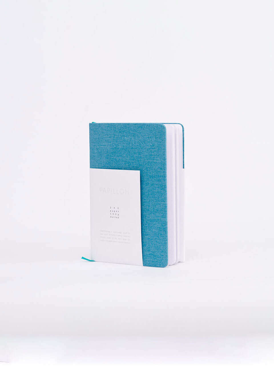 A linen notebook place beside a white block with a clean white background.
