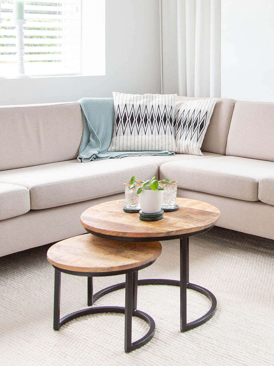 A cozy living room featuring a comfortable couch with white pillow covers with black stripped pattern, a stylish coffee table, and a dining table for gatherings.